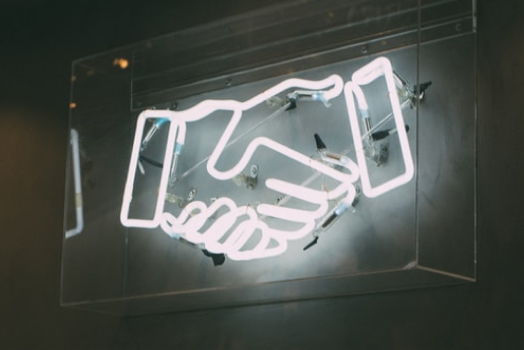 Photo of neon sigh of two hands in handshake