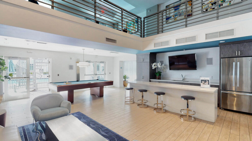 Community clubroom at The Point at Coral Gables featuring a pool table, TV, and kitchen.