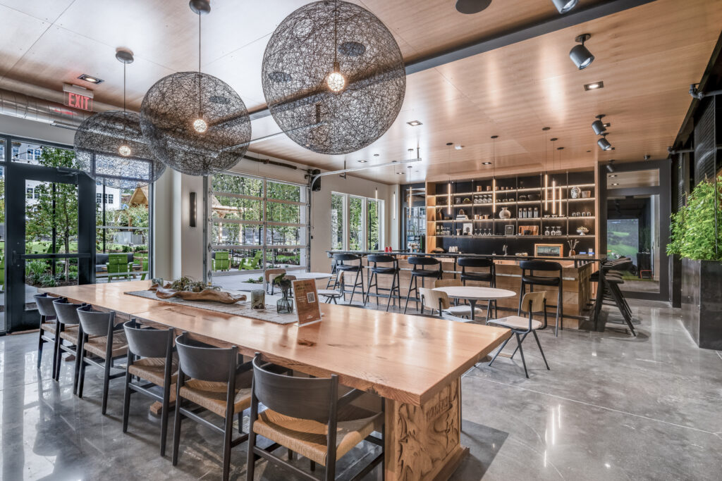 Modern clubroom at The Point at Green District. Includes tables, chairs, bar, wine and beer taps and outdoor seating.