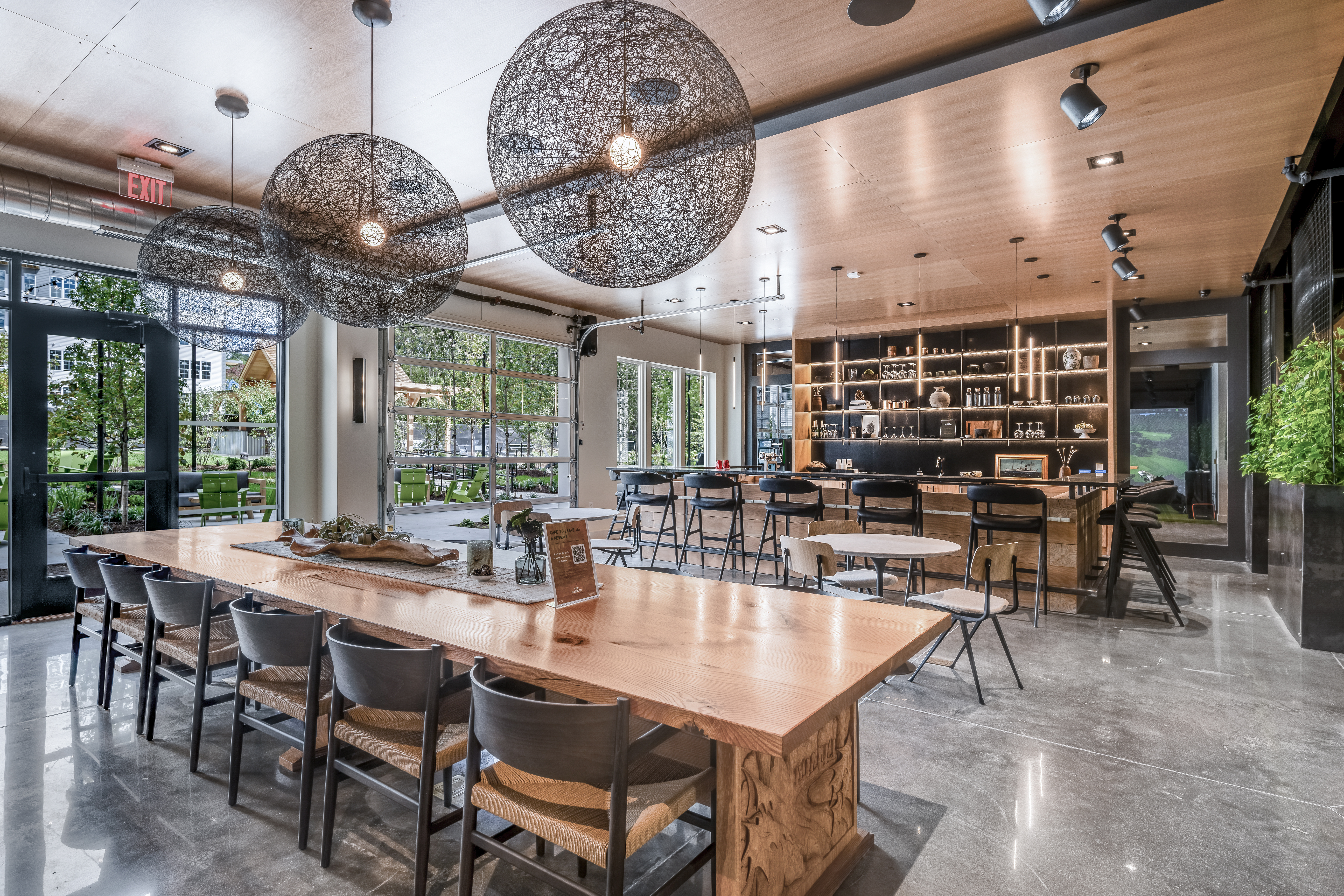 Modern clubroom at The Point at Green District. Includes tables, chairs, bar, wine and beer taps and outdoor seating.