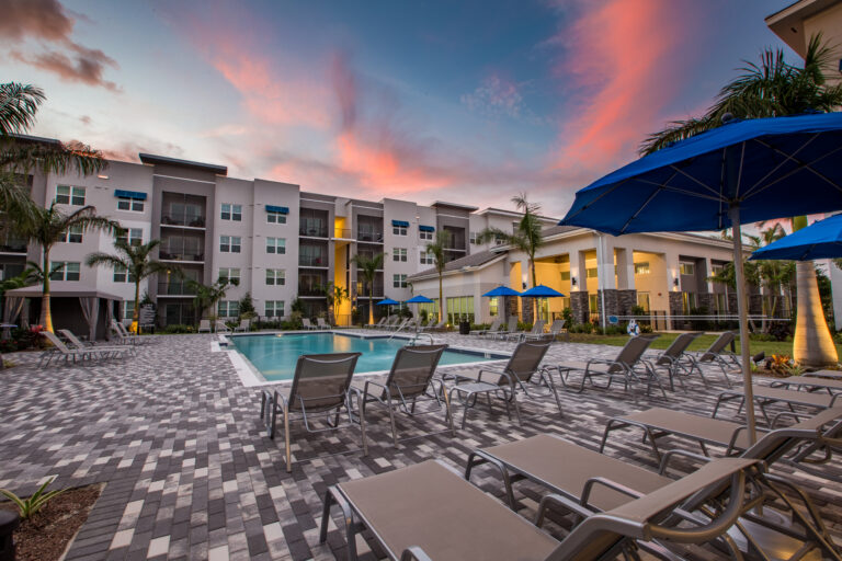 Outdoor resort style pool with lounge chairs and umbrellas at The Point at Palm Beach Grove